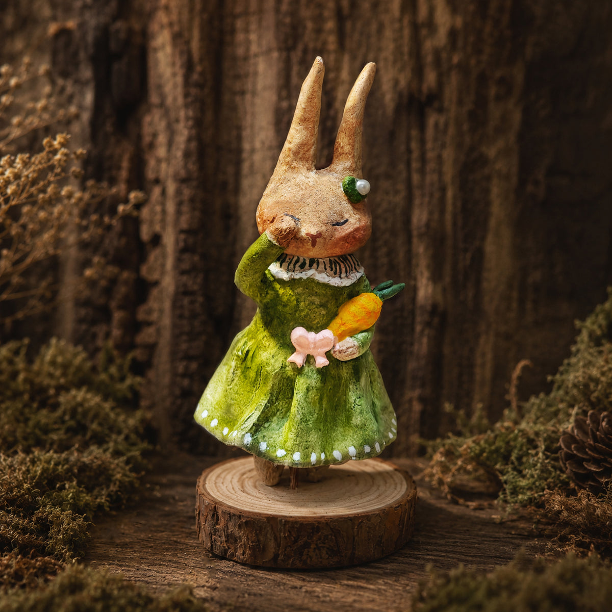 Willowwick rabbit doll in a green dress holding a small carrot.
