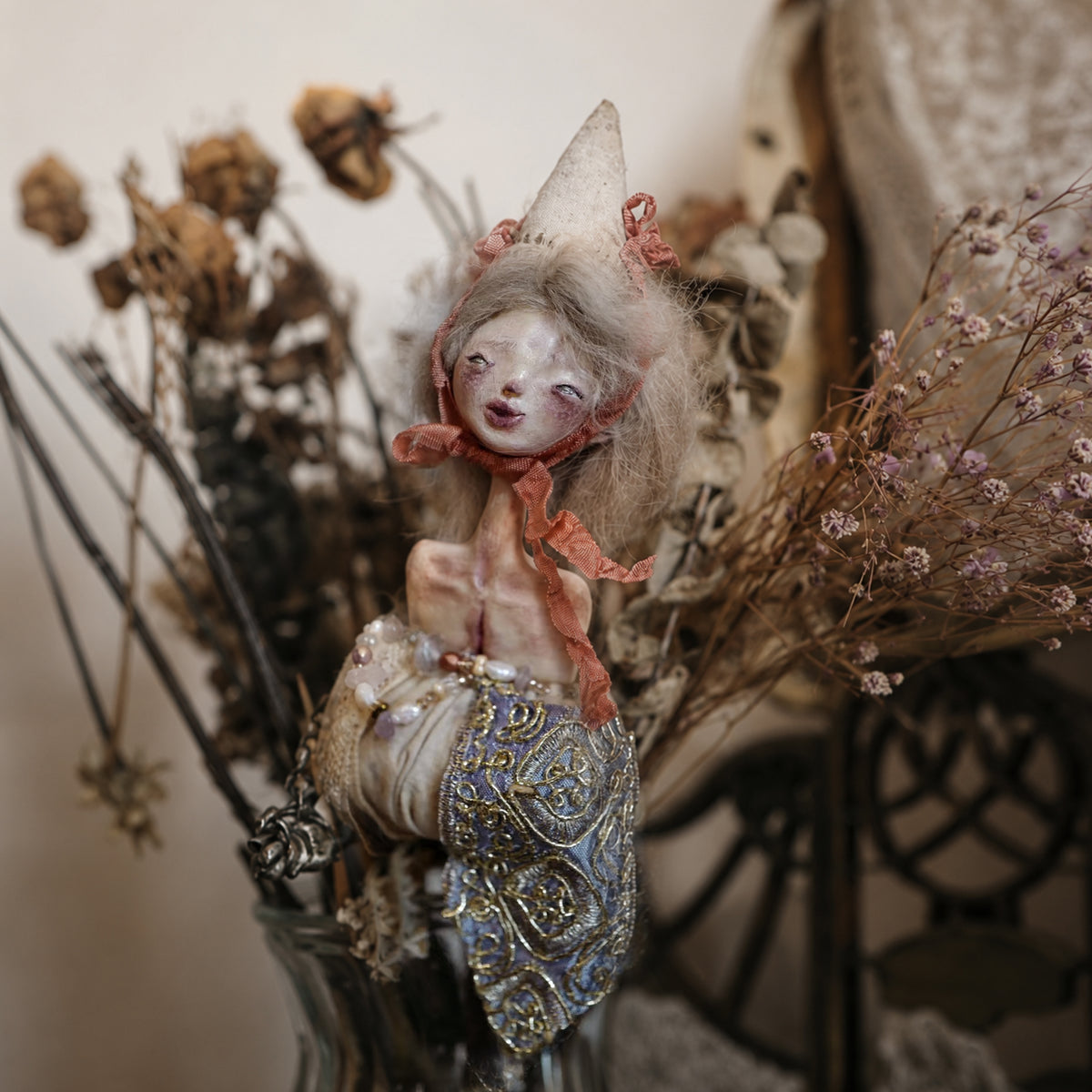 Lambwick doll hand-bell sculpture with pale hair, a cream cone hat and ornate blue-and-gold details.