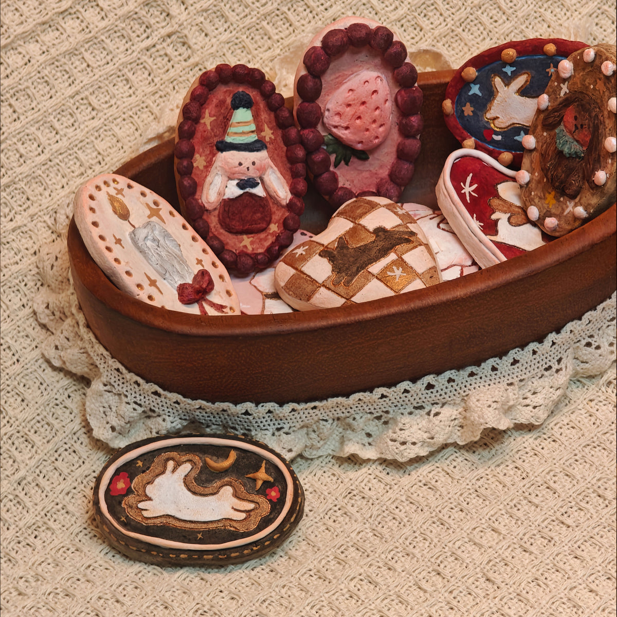 Winterwood Storybook brooch collection arranged in and beside an oval box.