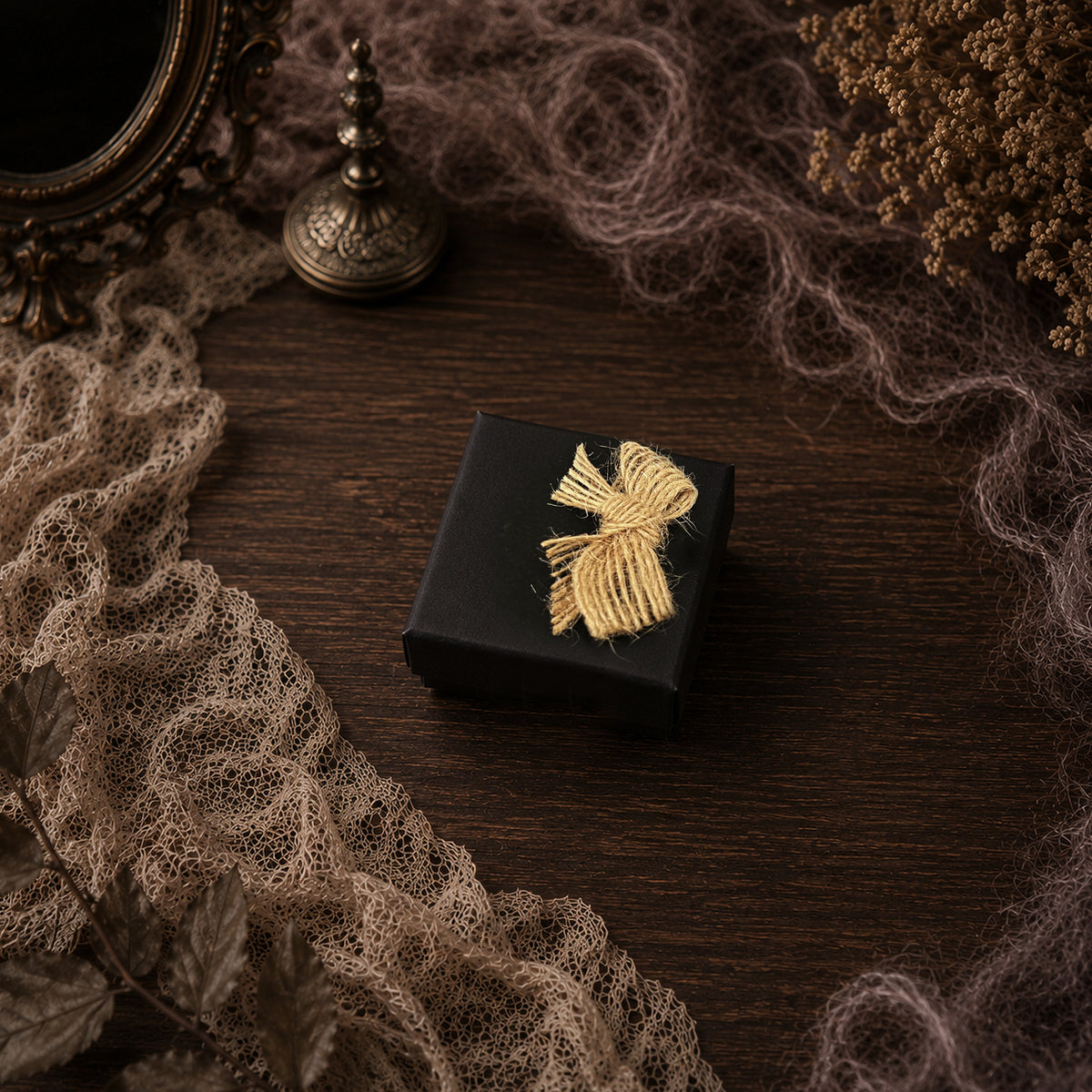 Black Lambwick gift box tied with pale cord, shown on brown lace.
