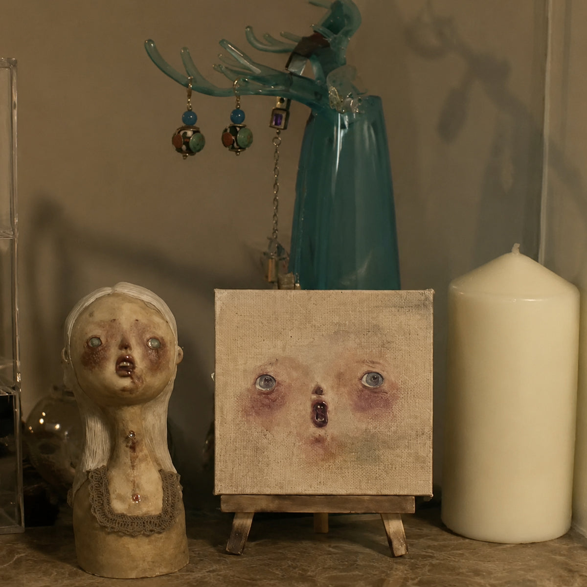 Lambwick clay-relief portrait on an easel beside a small bust and a candle.