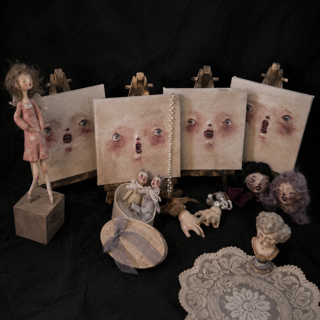 Lambwick clay-relief portraits displayed with art dolls and miniature figures against a dark background.
