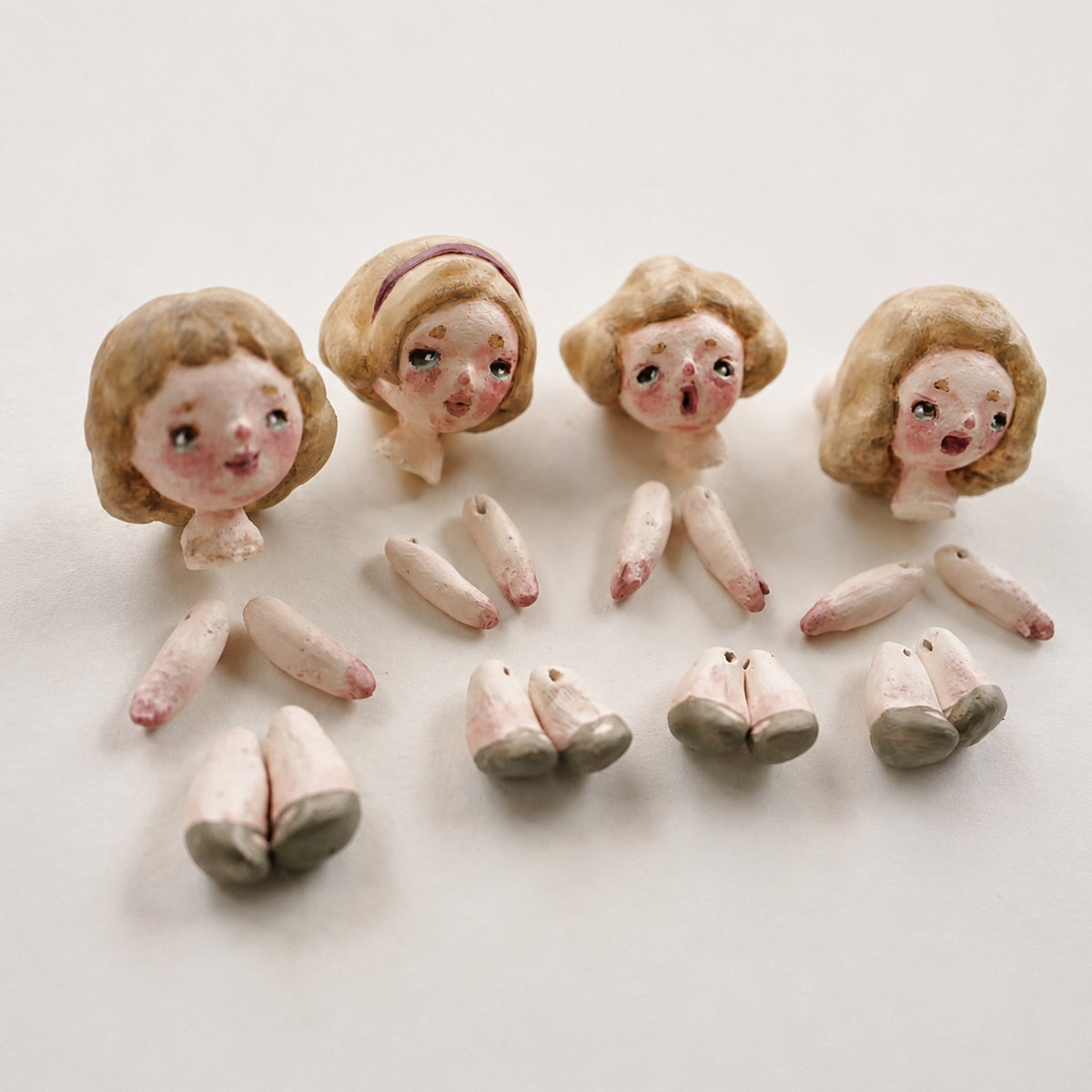 Lambwick miniature doll heads and separate arms and legs laid out before assembly.
