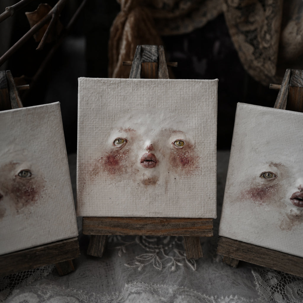 Three Lambwick clay-relief portraits with different painted eyes and expressions.