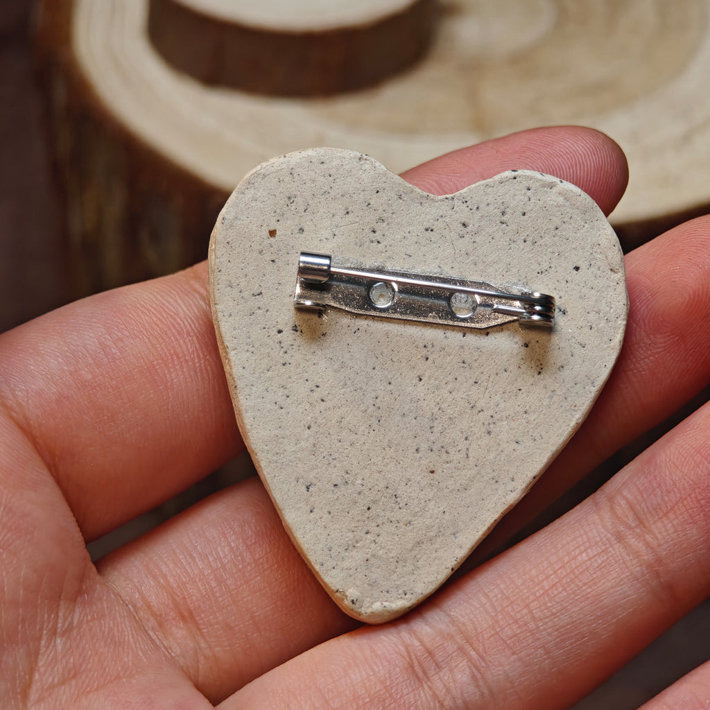 Plain back of a heart-shaped Winterwood brooch with a metal pin clasp.