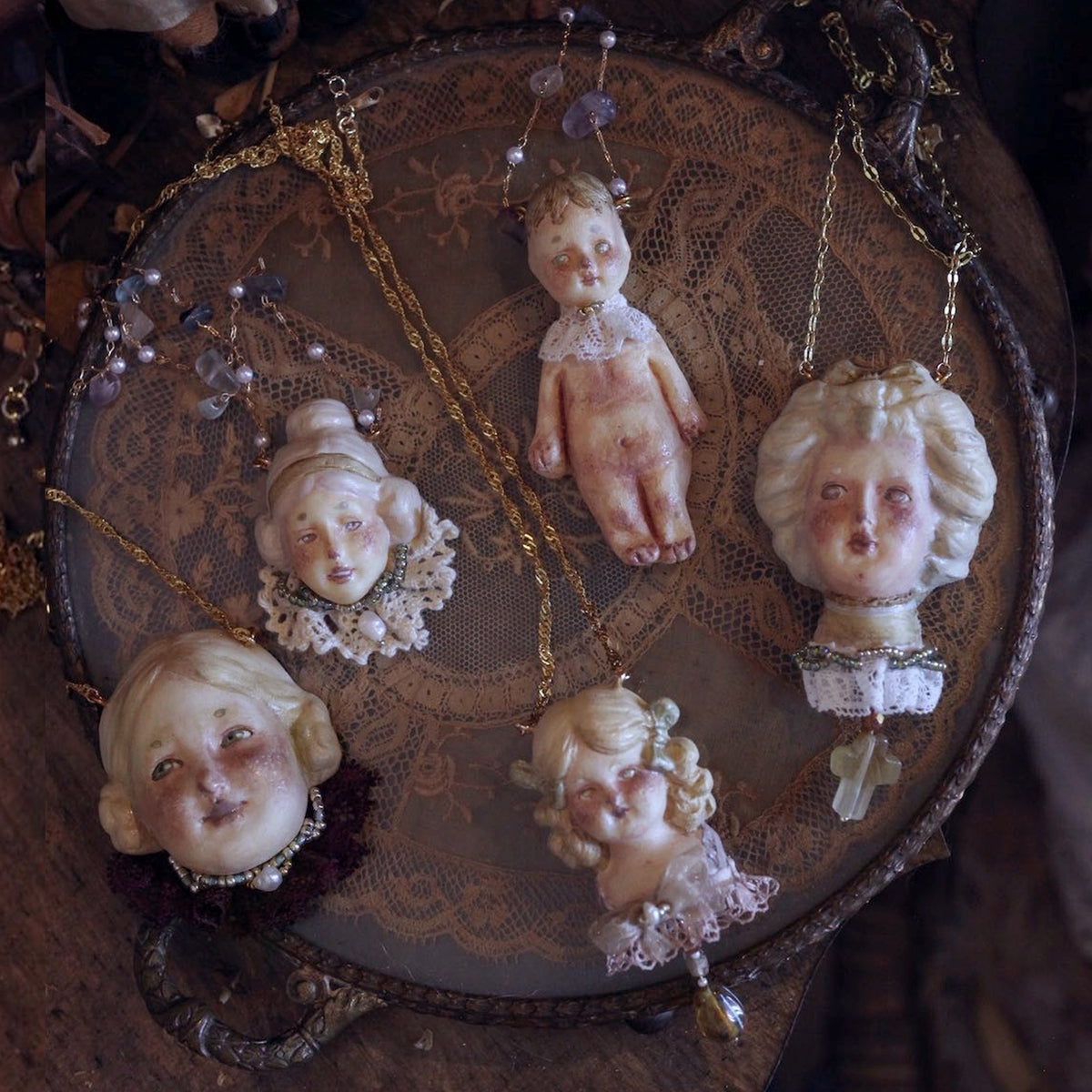 Lambwick doll necklace styles arranged together on a round wooden tray.