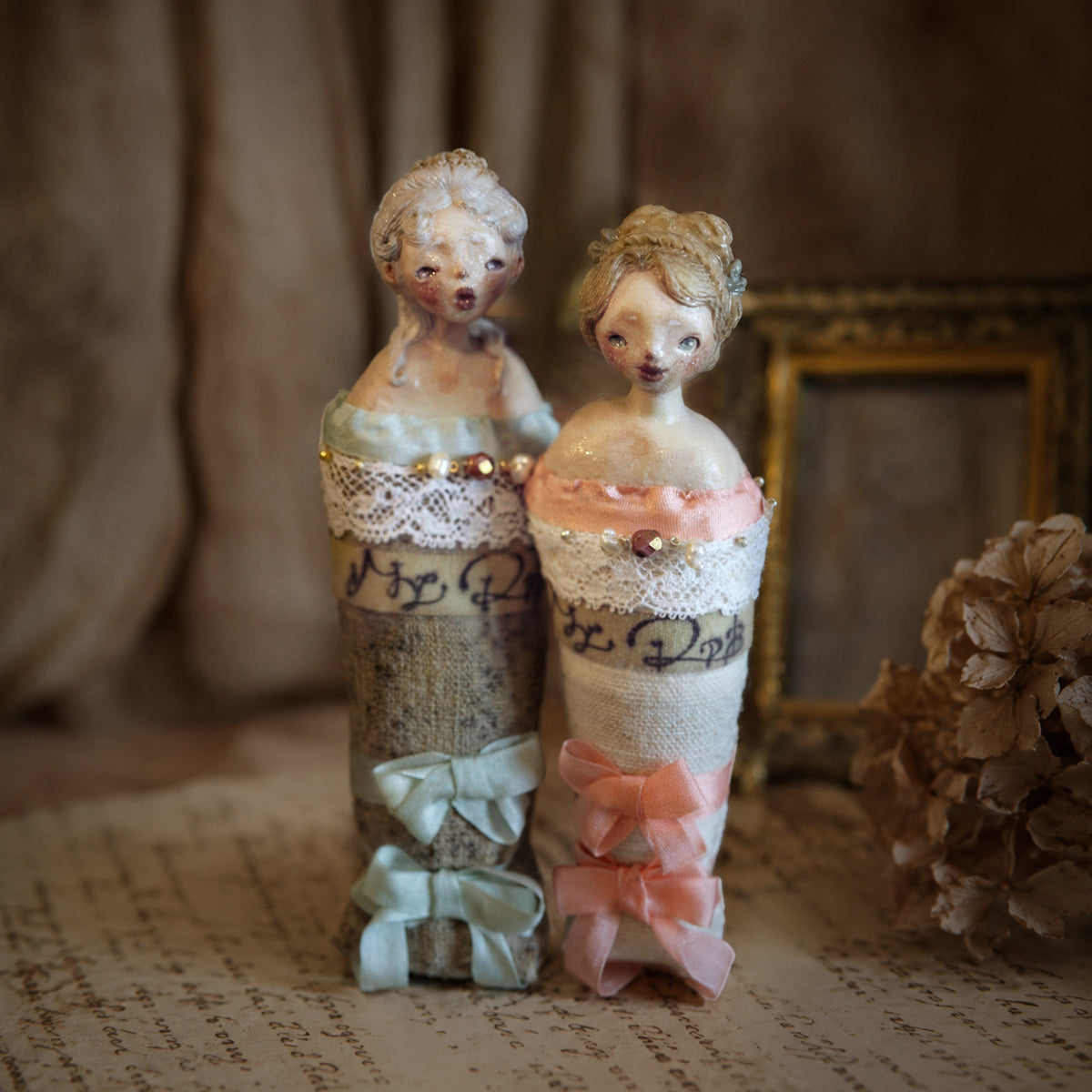 Blue- and pink-ribbon Lambwick Twin Series doll brooches displayed side by side.
