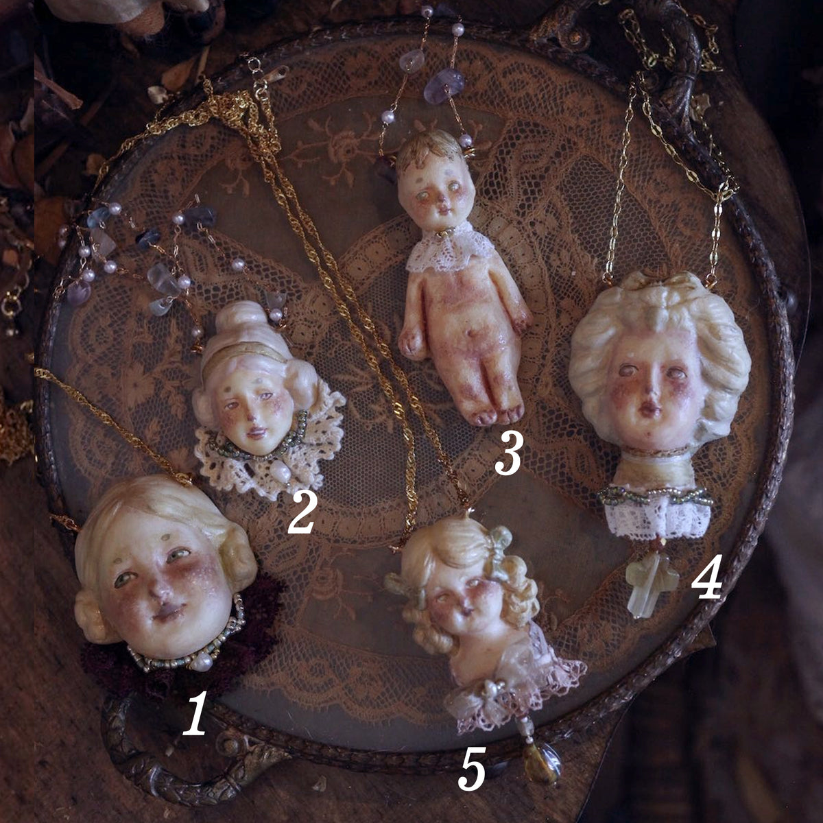 Numbered comparison of five Lambwick doll necklace designs arranged on a wooden tray.