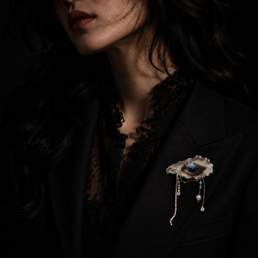 Lilith Veil Black & White Smoky shell-eye brooch worn on a black lace top.