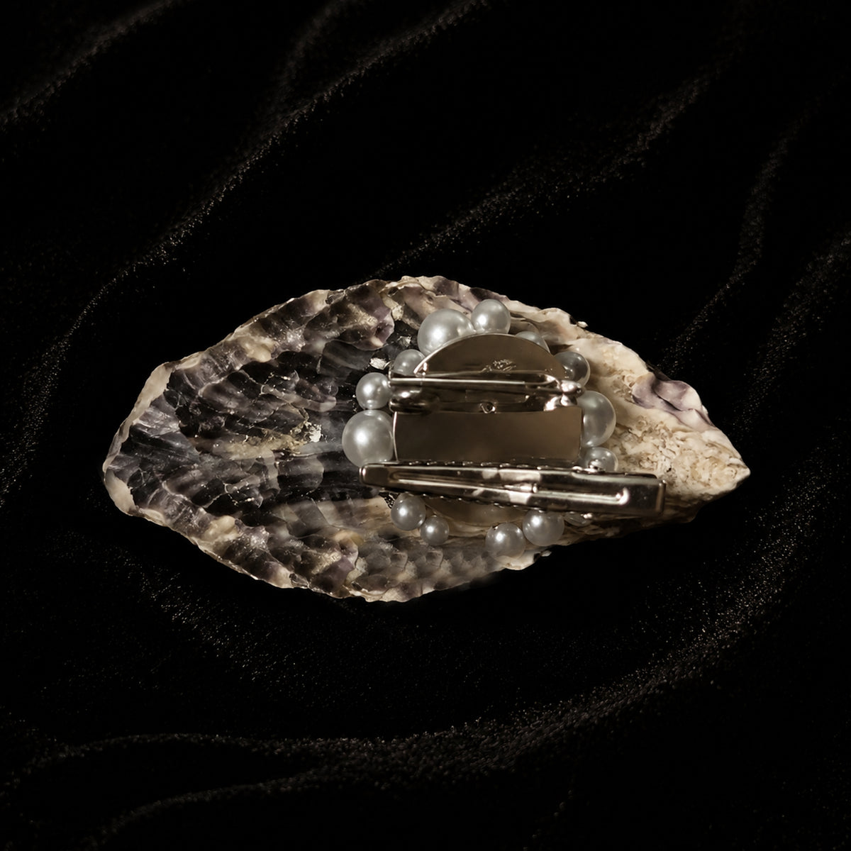 Reverse of a shell-eye piece showing the natural shell exterior and metal mounting hardware.