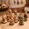 Numbered group of nine Willowwick Family rabbit dolls in different outfits on wooden bases.