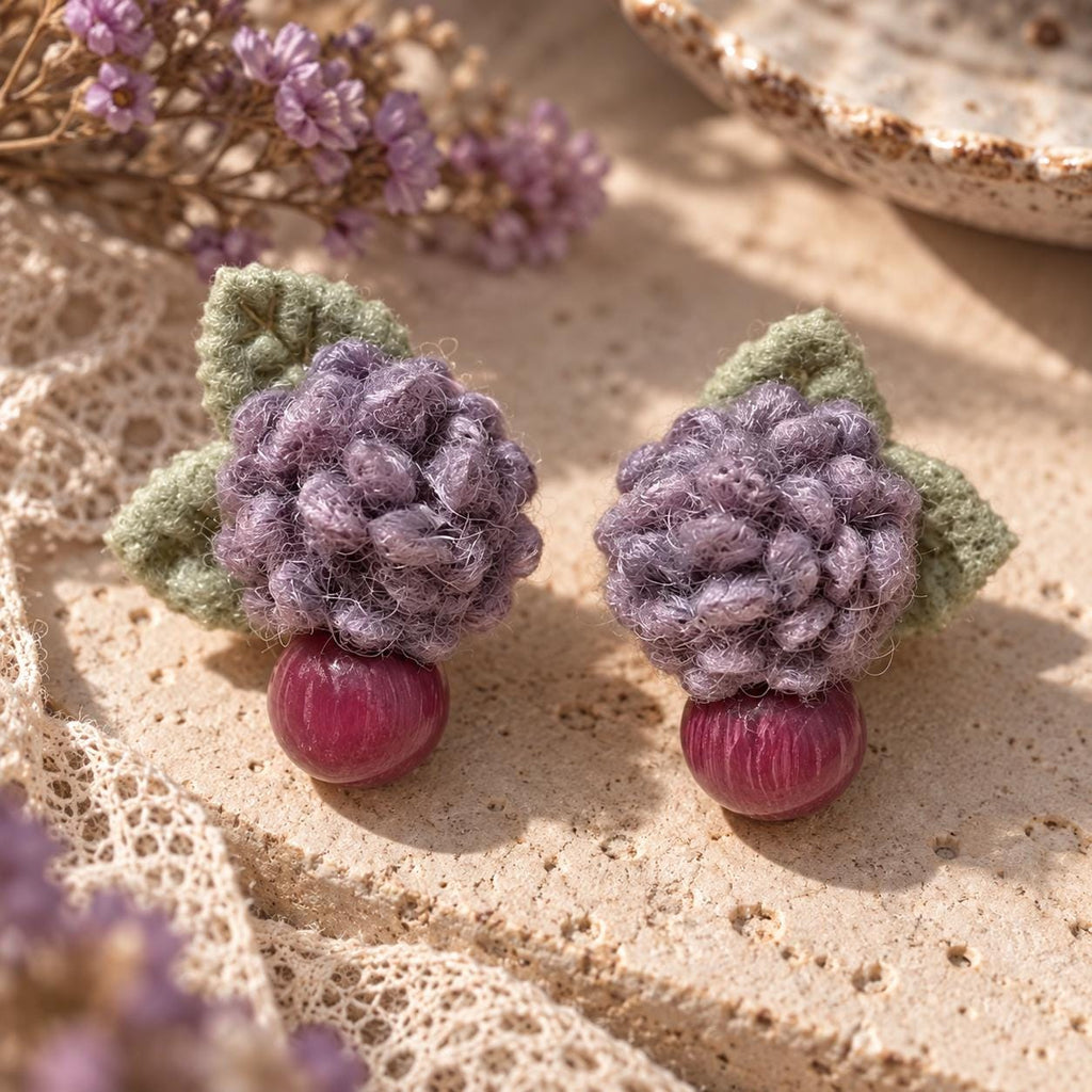 Close view of paired Lilac Berry earrings on limestone beside purple fabric.