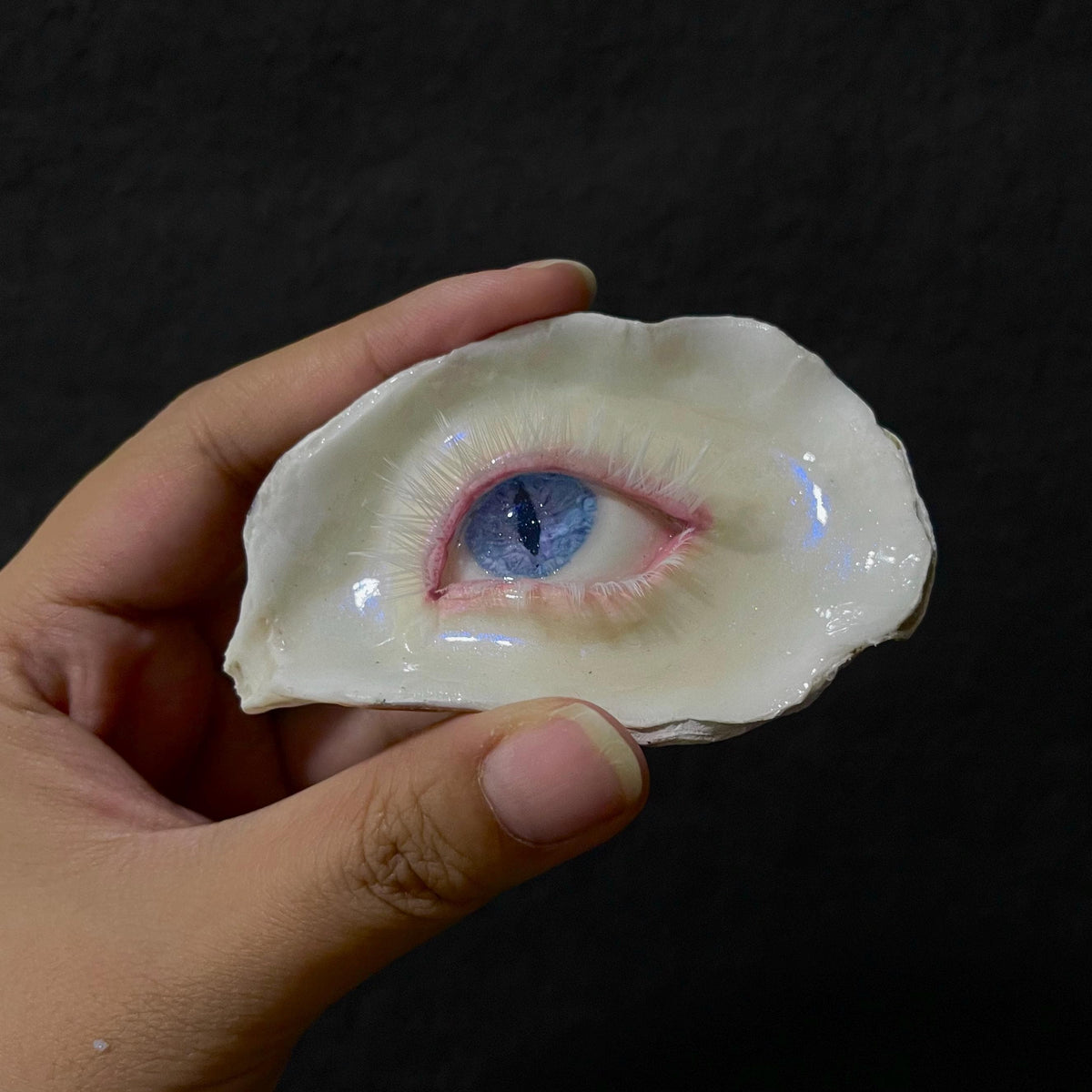 Close view of Nyx Cat blue slit-pupil eye in an ivory shell held in a hand.