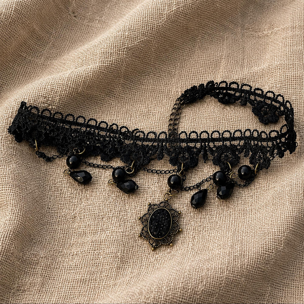 Black gothic choker laid flat to show its beaded loops, lace band and teardrop pendant.