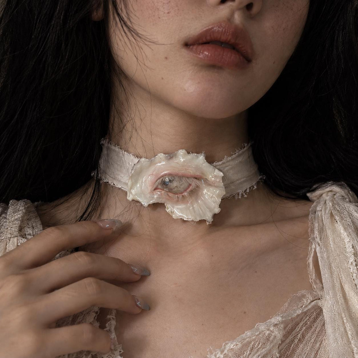 Morrow Eye oyster-eye piece worn as an ivory-ribbon choker.