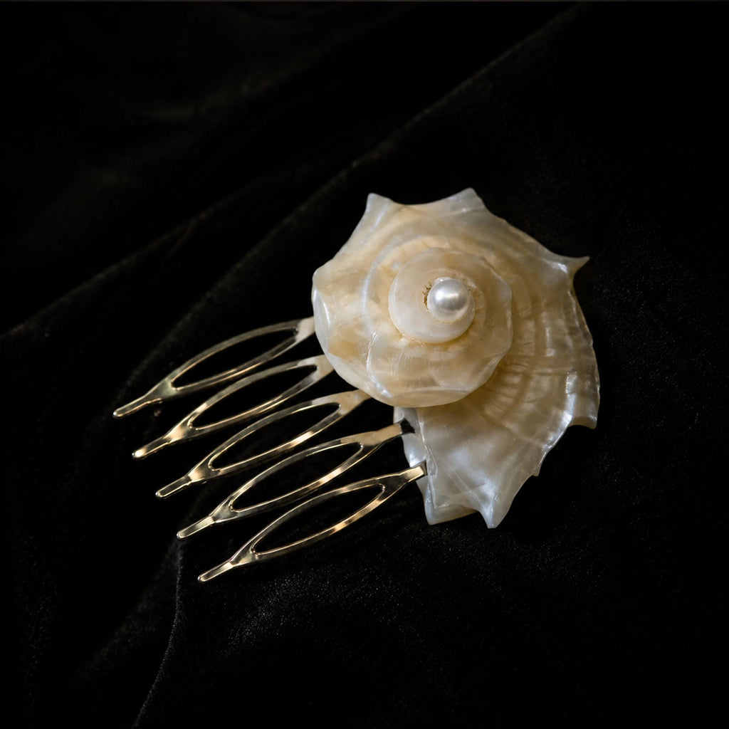 Conch-shell bridal hair comb with a pale spiral shell on black velvet.