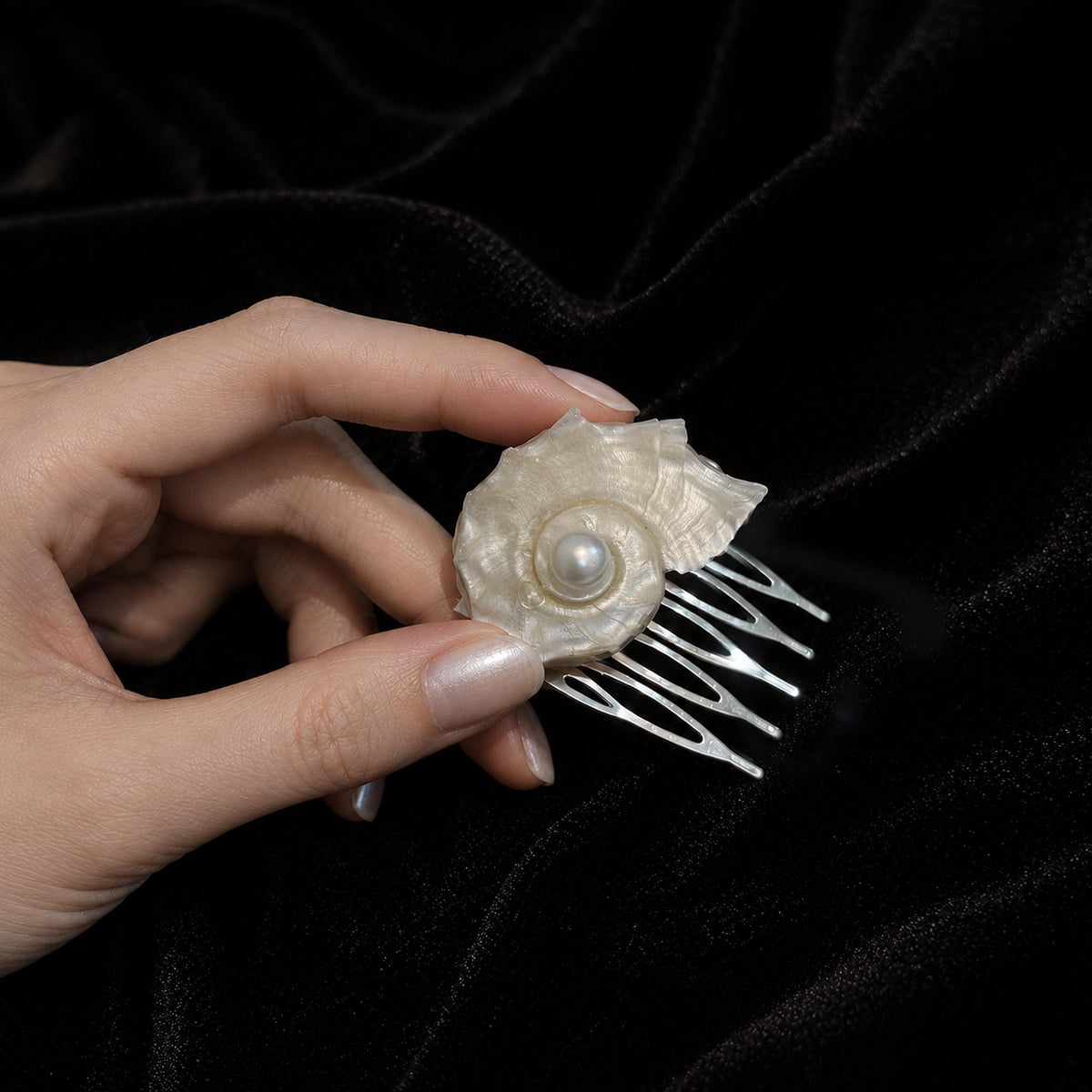 Conch-shell bridal hair comb held in a hand to show its scale.