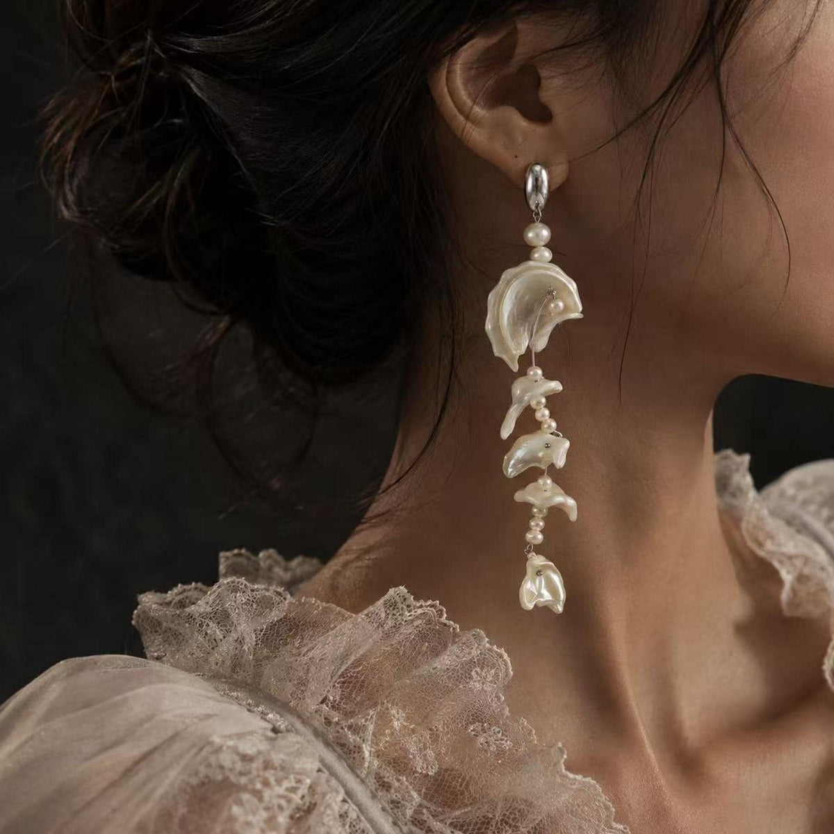 Shell-fragment drop earring with pale wavy sections and small connecting beads shown worn.