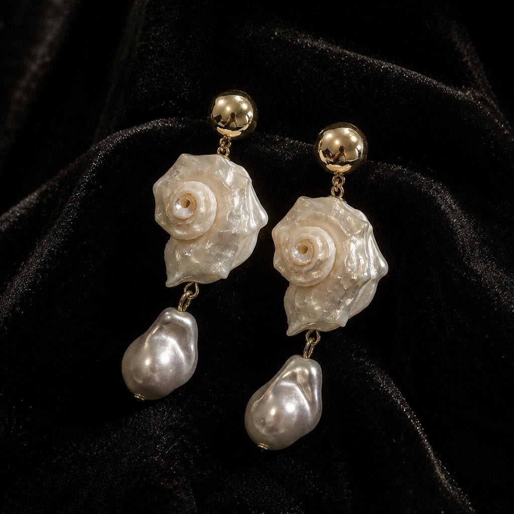 Pair of spiral conch-shell earrings with gold-tone studs and large pale teardrop beads.