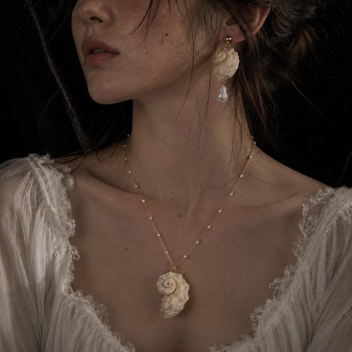 Matching spiral conch-shell necklace and earring shown worn together.