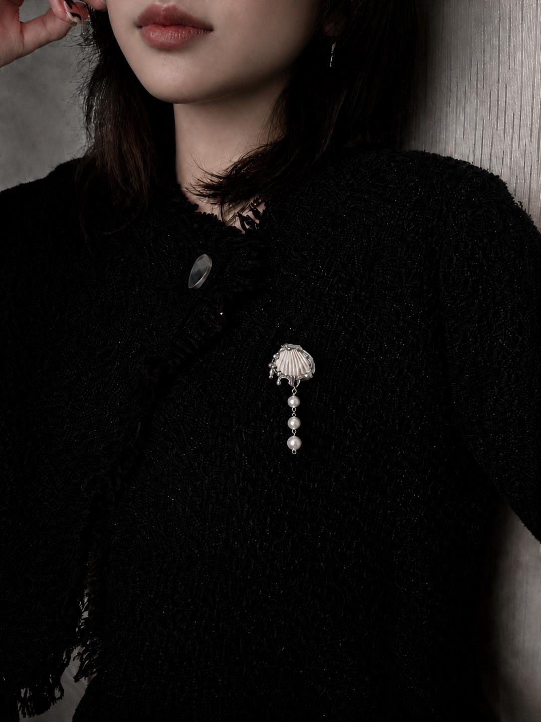 Shell Pearl Drop worn as a brooch on a black knitted top.
