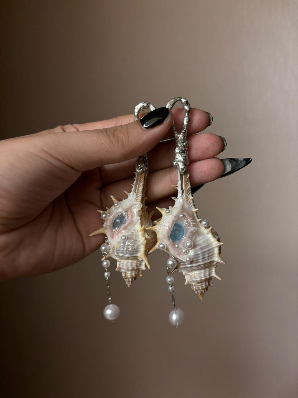 Two Conch Eye Talisman pieces with large metal pin attachments, held together.