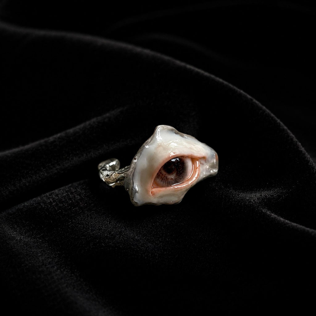 Brown-pupil oyster-eye ring resting at an angle on black velvet.