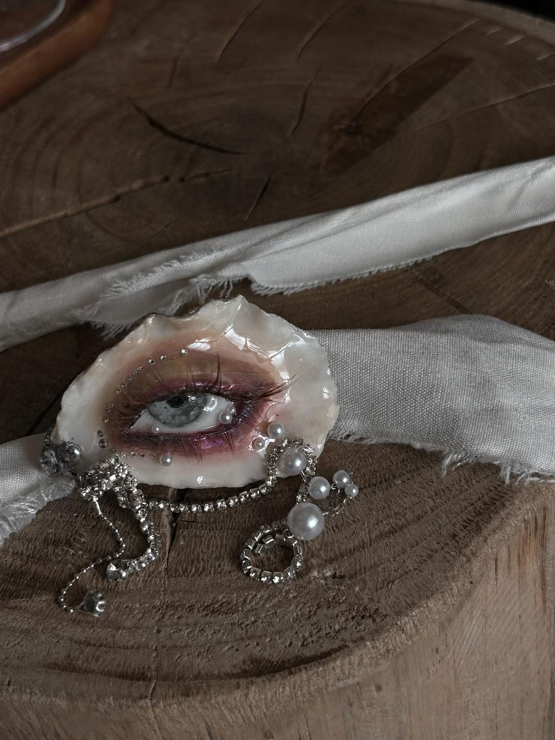 Brown Smoky Oyster Eye on pale ribbon displayed on a wooden surface.