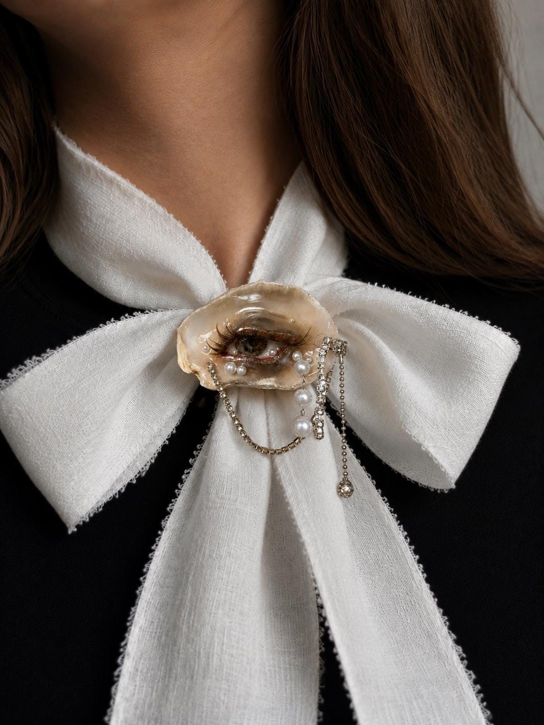 Brown Smoky Oyster Eye worn at the center of an ivory ribbon bow.