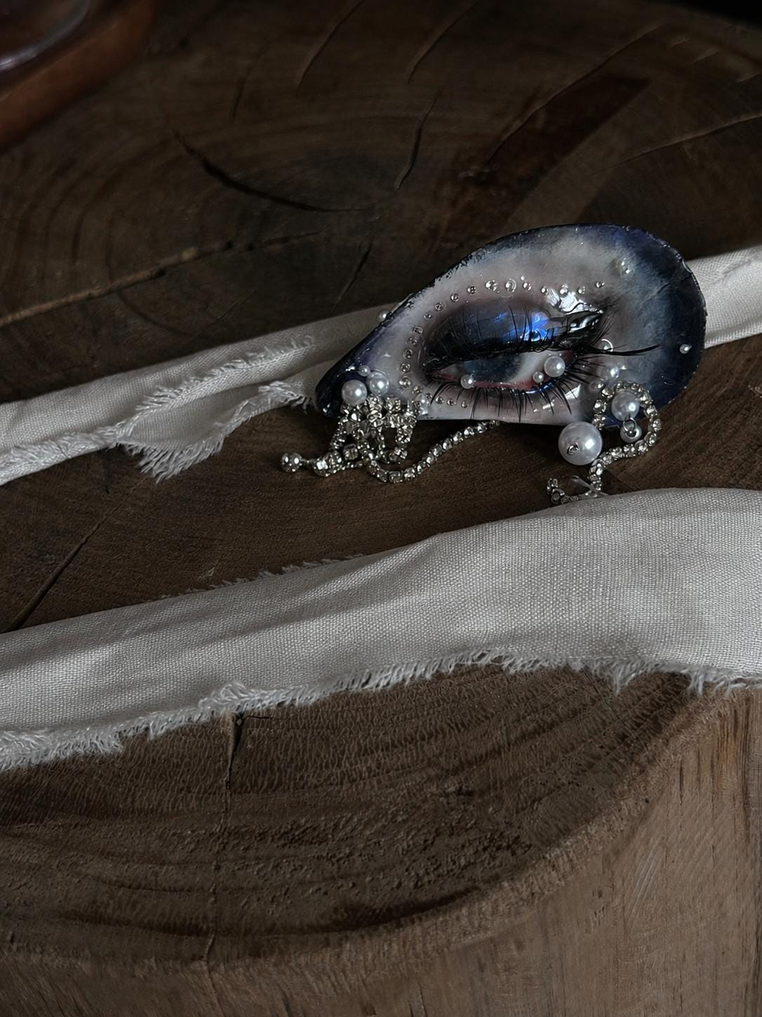 Blue Smoky Shell Eye displayed on pale ribbon over a wooden surface.