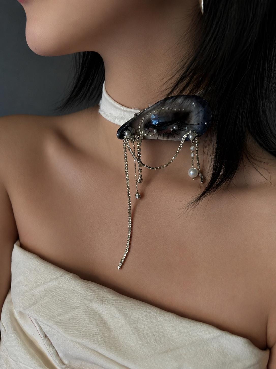 Blue Smoky Shell Eye worn as a pale-ribbon choker above an ivory top.