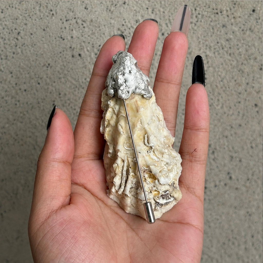 Reverse of a blue-eye oyster-shell brooch showing the natural shell back and long metal pin.