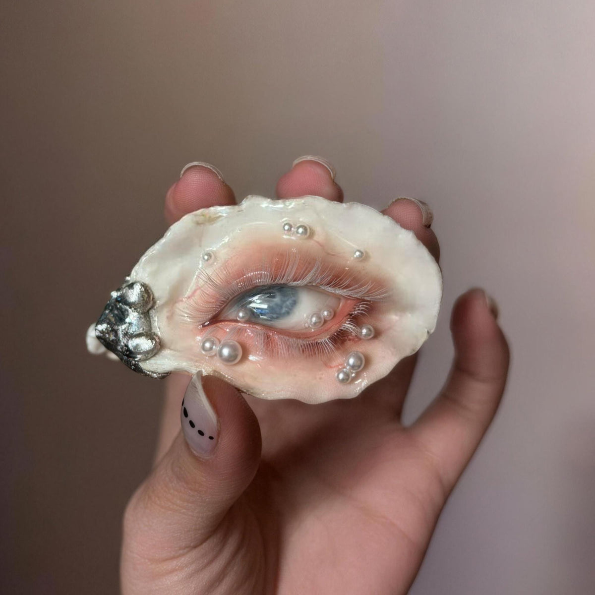 White-Lash Blue Oyster Eye held in a hand, showing pale lashes and pearl-like accents.