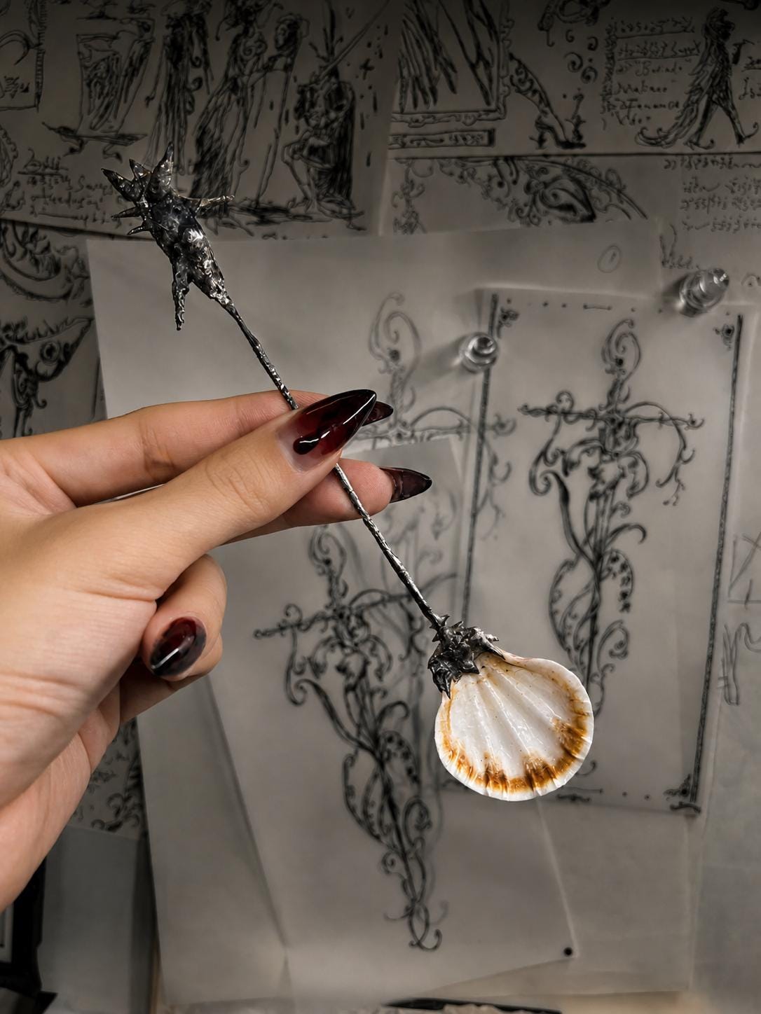 Decorative shell spoon held at an angle to show its shell bowl and long metal handle.