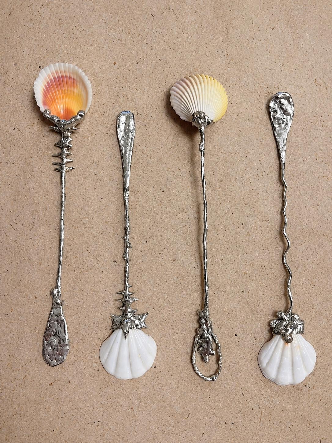 Three decorative shell spoons arranged side by side to show their bowl and handle designs.