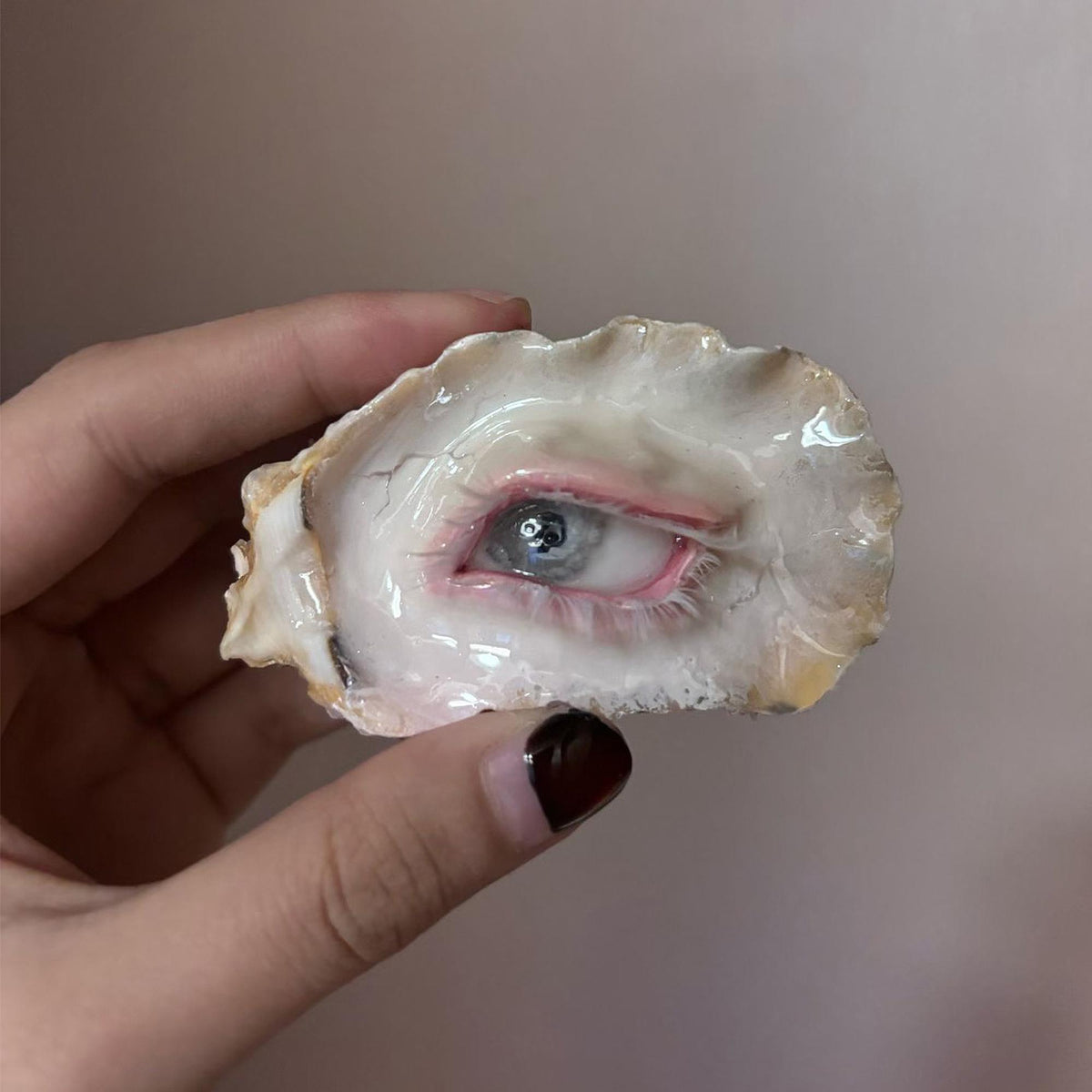 Pearl-Free White-Water Blue Oyster Eye held in a hand, showing the pale blue iris and pink eyelid.