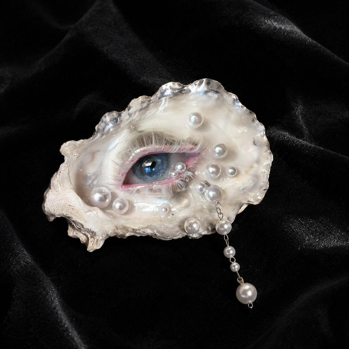 Pearl-Drop White-Water Blue Oyster Eye with a blue iris and pearl-like accents on black velvet.