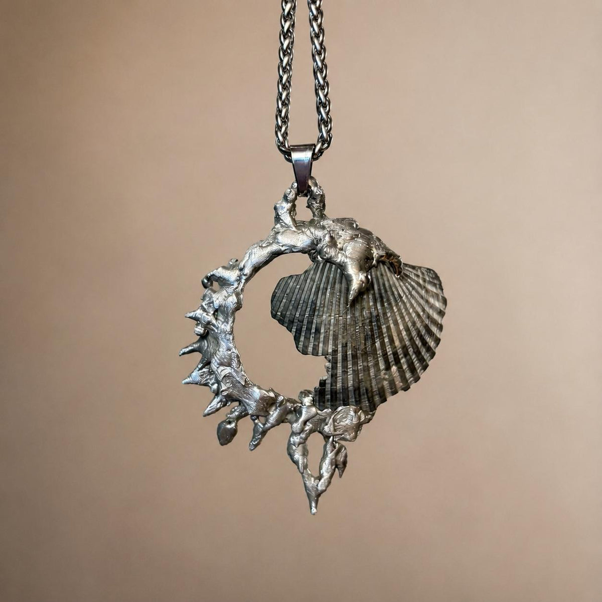 Reverse of the Spiked Conch Loop Talisman showing a ridged shell and spiked metal loop.