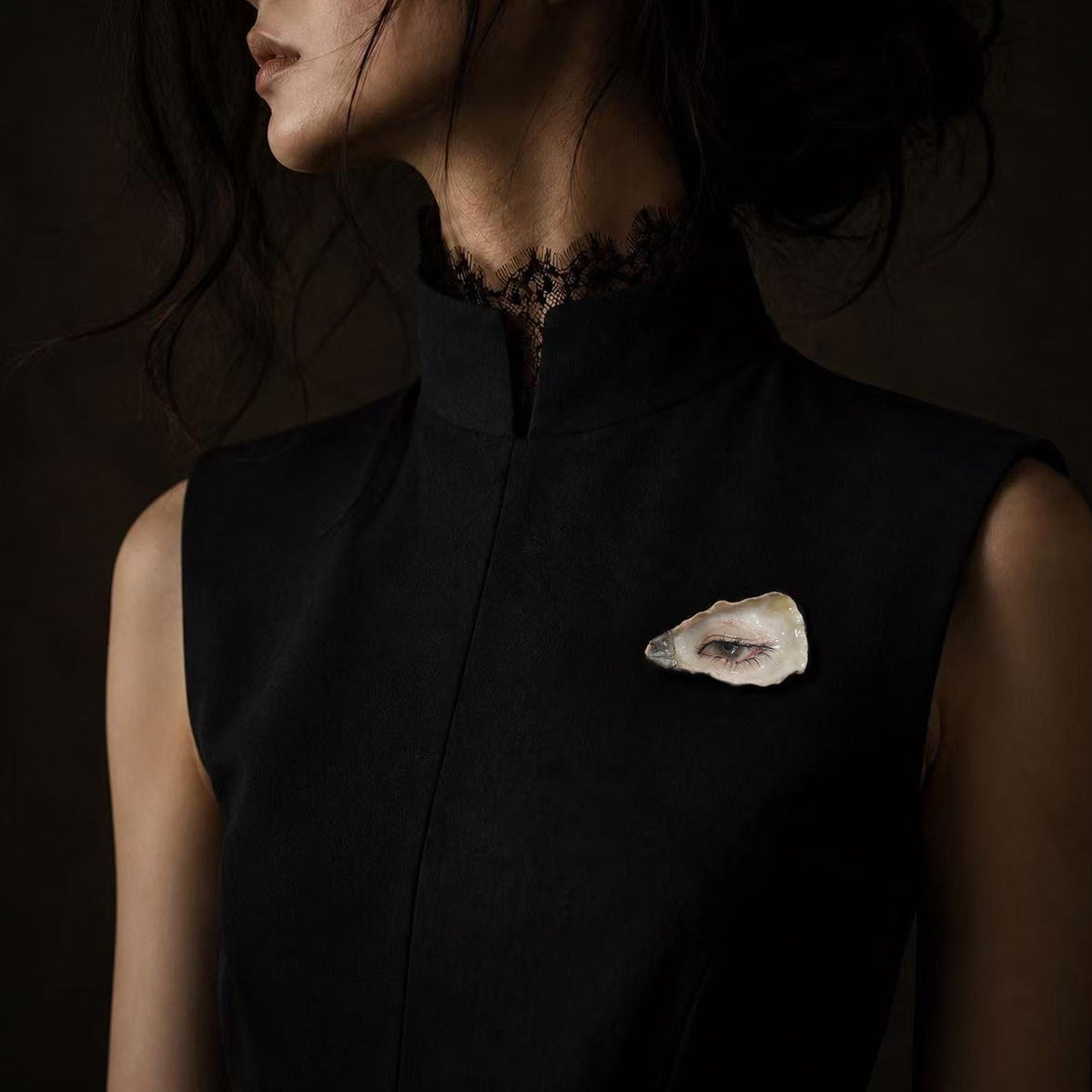 Nyra Black-Lash Oyster Eye brooch worn on a sleeveless black top.