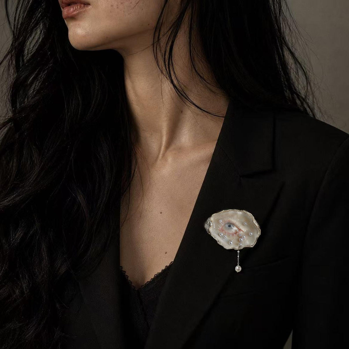 Nyra Unimpressed Gaze shell-eye brooch worn on a black blazer.