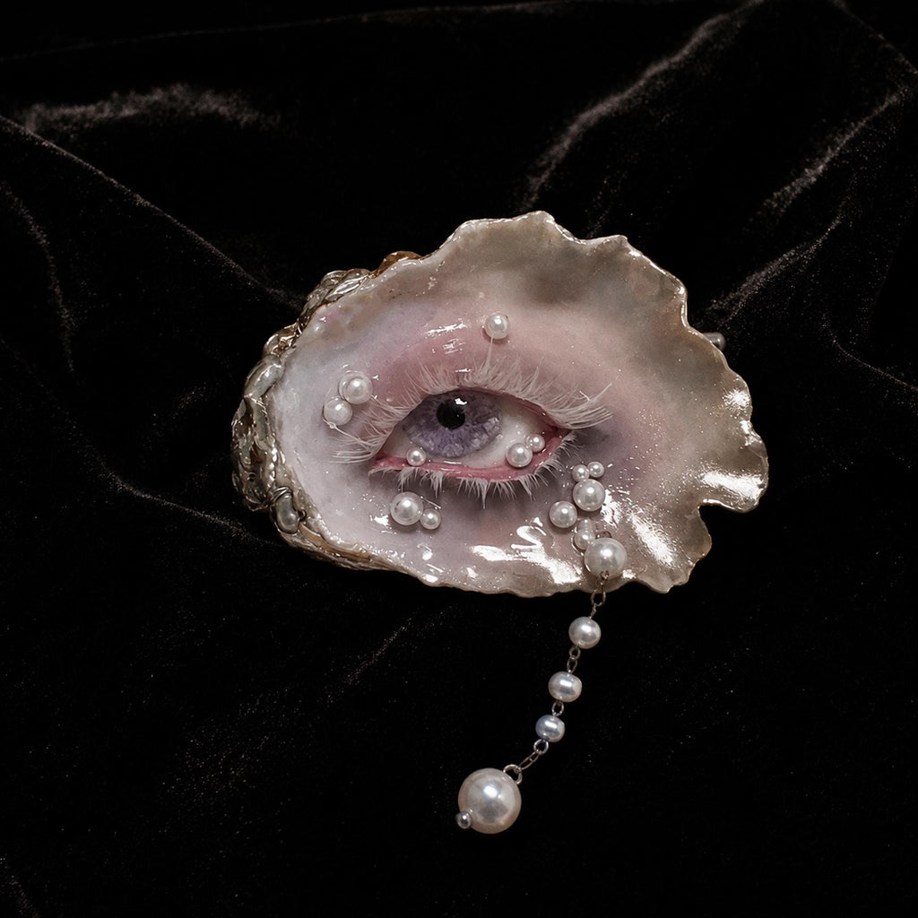 Nyra Lavender Gaze oyster eye with pale bead accents and a hanging drop on dark velvet.