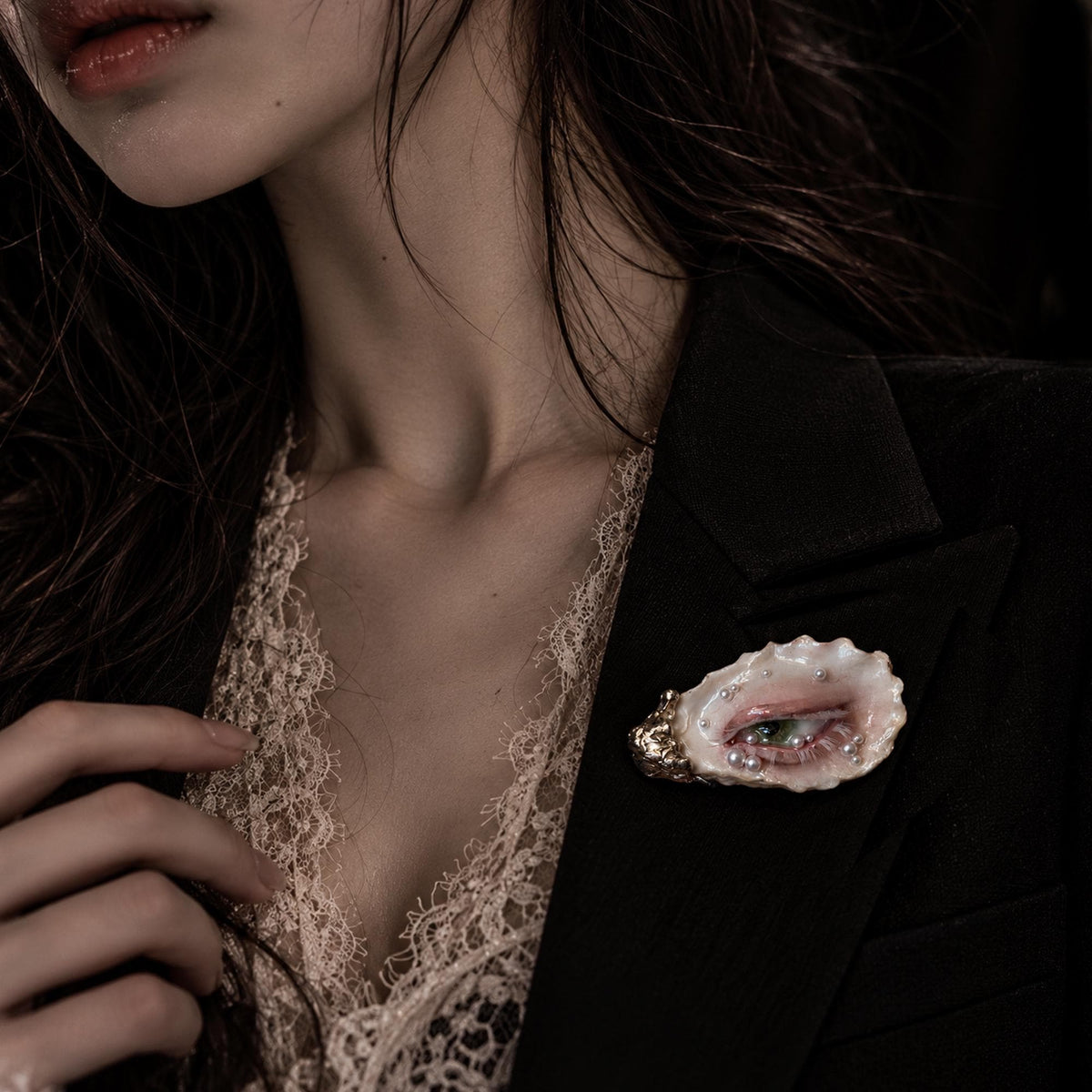 Nyra Nacre Veil shell-eye brooch worn on a dark blazer over an ivory blouse.