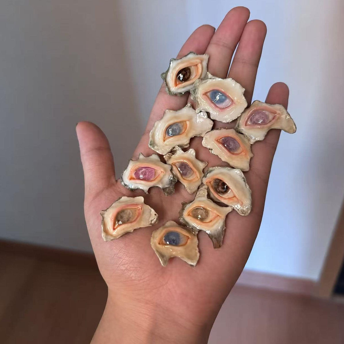 Assortment of small shell-eye pieces with different iris colors displayed across a palm.