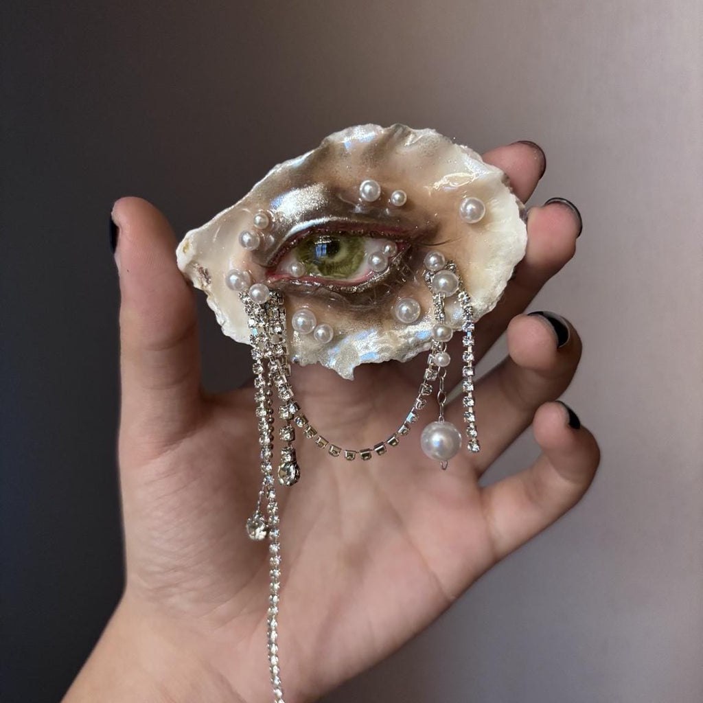 Lilith Veil Emerald Siren oyster eye shown across a palm to show its scale and long chains.